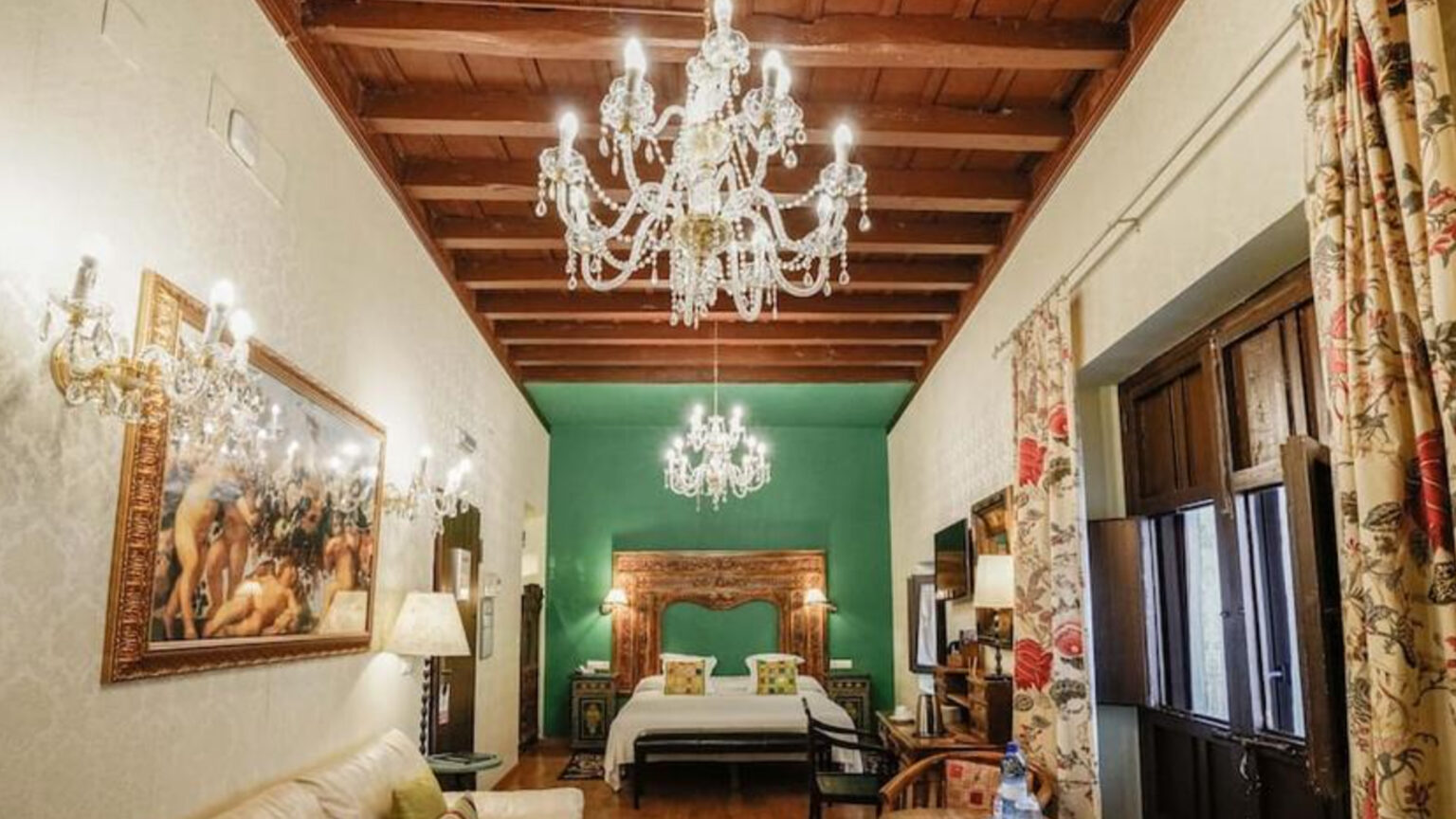 El Rey Moro Hotel room with chandeliers, a wooden ceiling, and a green accent wall