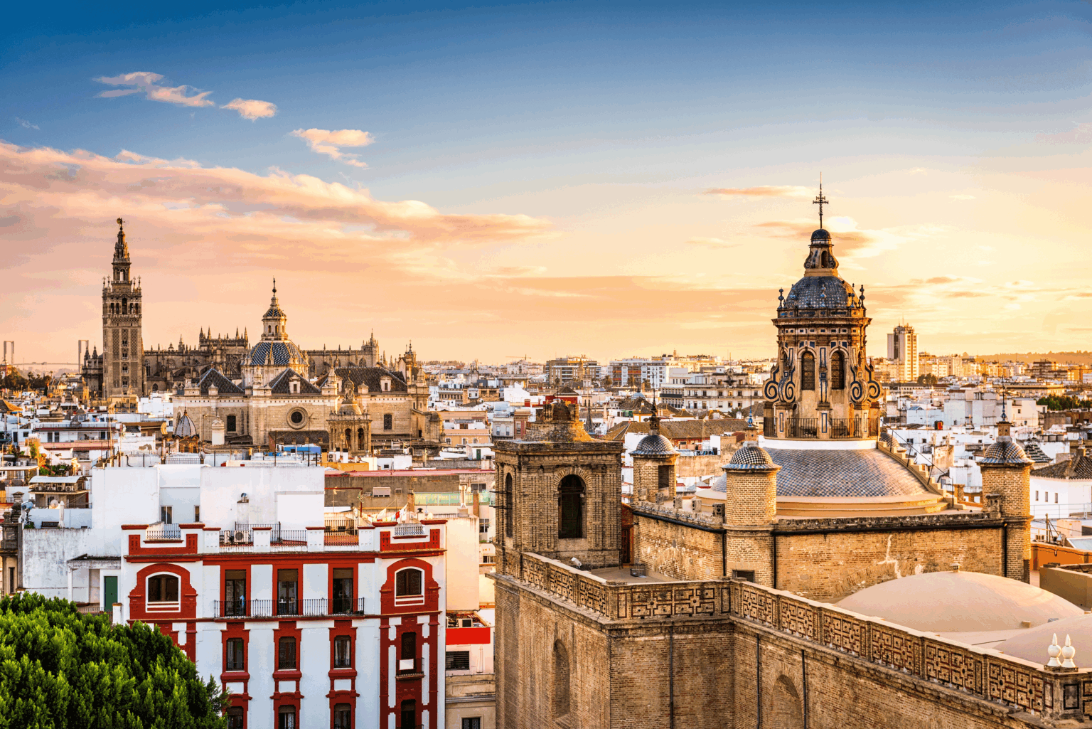 Seville rooftops and the Giralda tower beneath a warm sunset sky